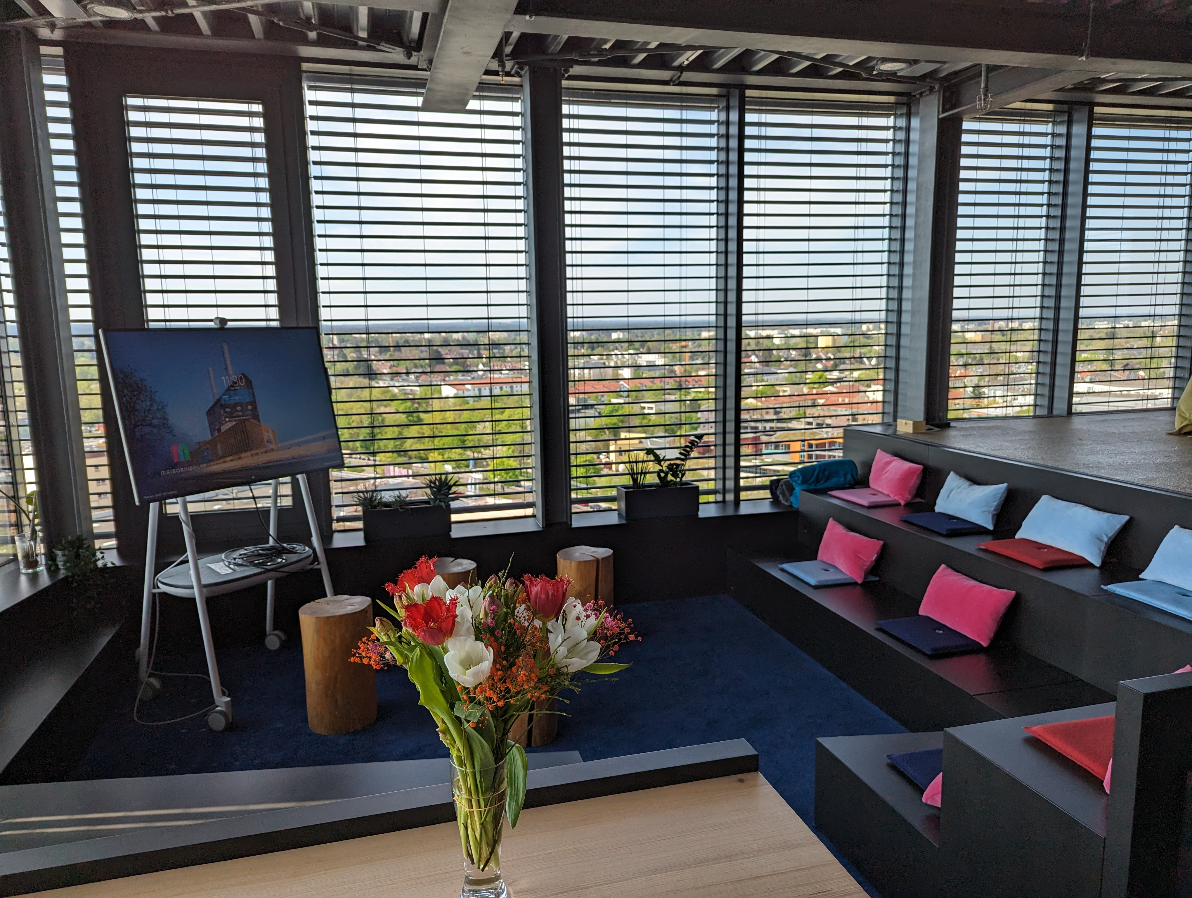 a comfortable-looking, modern seating area with windows in the background, showing a view over the city